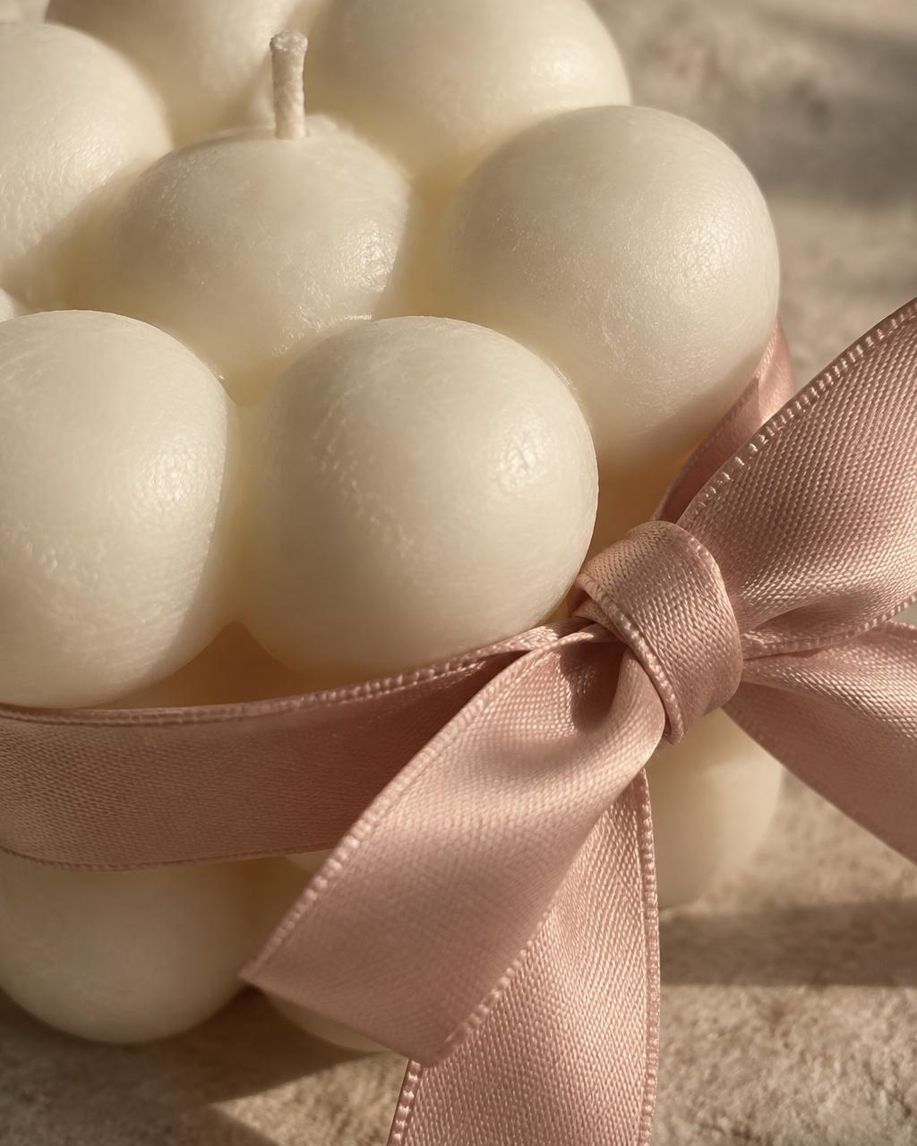 An intimate study of ivory wax spheres and the fine weave of a blush satin bow